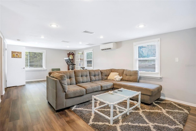 living room featuring a wall mounted air conditioner, visible vents, dark wood finished floors, and a healthy amount of sunlight