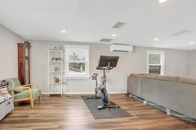 exercise room featuring recessed lighting, a wall unit AC, wood finished floors, and baseboards