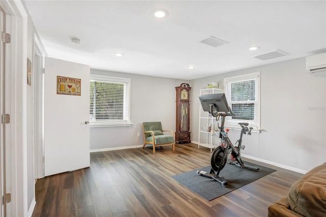 exercise room featuring plenty of natural light, a wall mounted air conditioner, dark wood-style floors, and visible vents