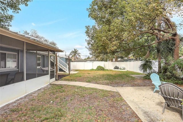 view of yard with a sunroom, a fenced backyard, a patio area, and stairs