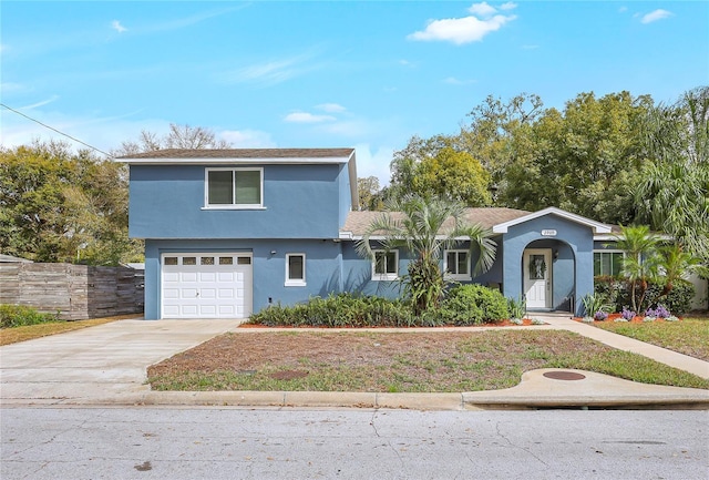 view of front facade featuring an attached garage, stucco siding, fence, and concrete driveway