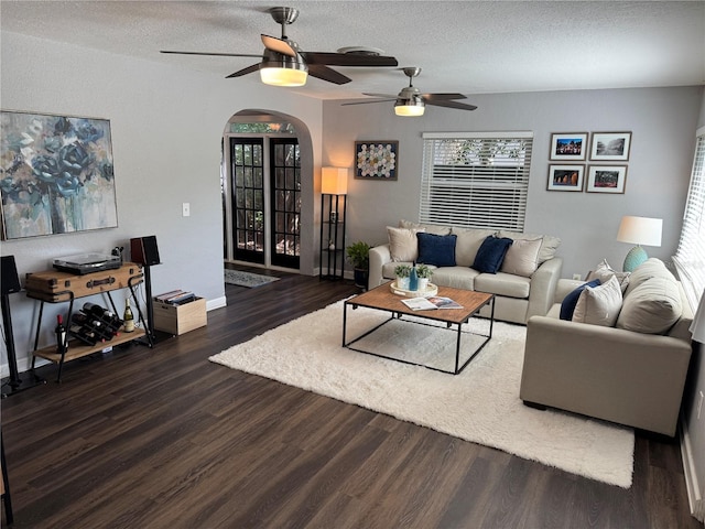 living room with arched walkways, a ceiling fan, wood finished floors, a textured ceiling, and baseboards