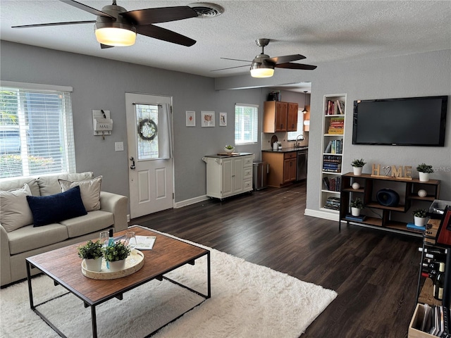 living area featuring a ceiling fan, dark wood finished floors, and a textured ceiling