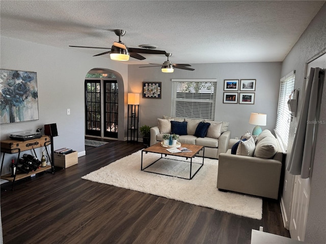 living area featuring arched walkways, wood finished floors, a textured ceiling, and a ceiling fan