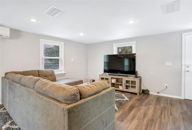 living room with wood finished floors, recessed lighting, baseboards, and a wall mounted AC