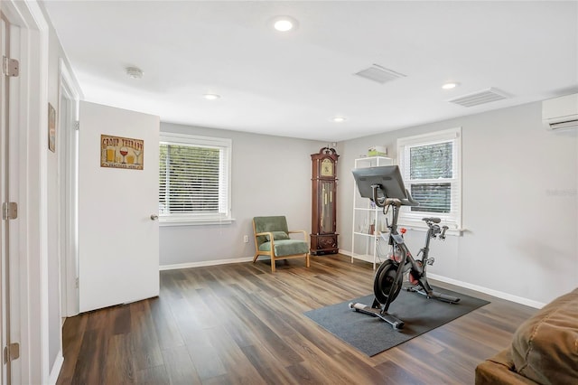 exercise room with healthy amount of natural light, wood finished floors, an AC wall unit, baseboards, and recessed lighting