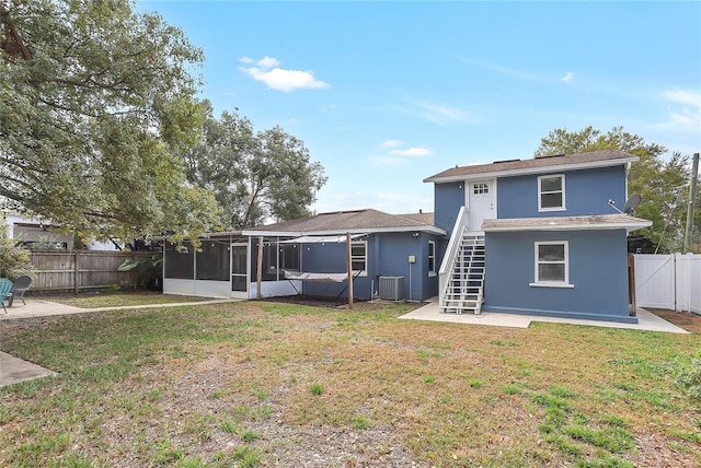 rear view of property with central AC, a sunroom, stucco siding, and stairway
