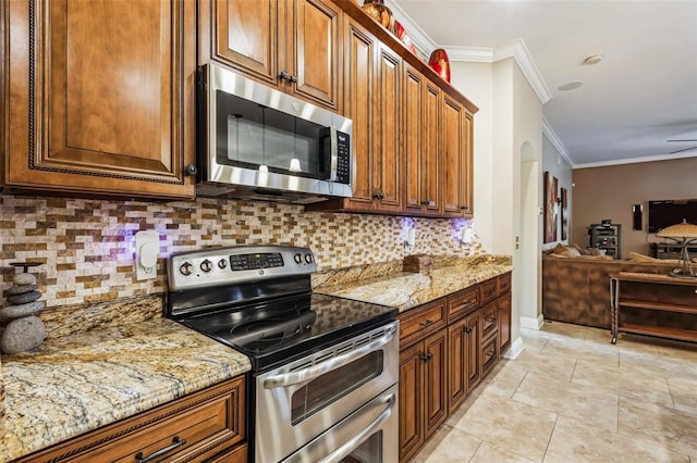 kitchen with stainless steel appliances, tasteful backsplash, light stone counters, light tile patterned floors, and crown molding