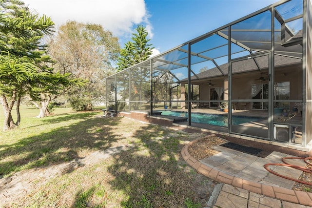 view of yard with ceiling fan, glass enclosure, and a patio