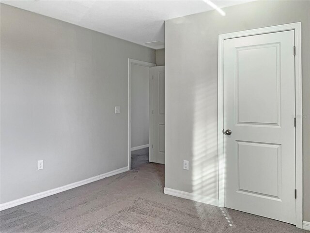unfurnished bedroom featuring light carpet and baseboards