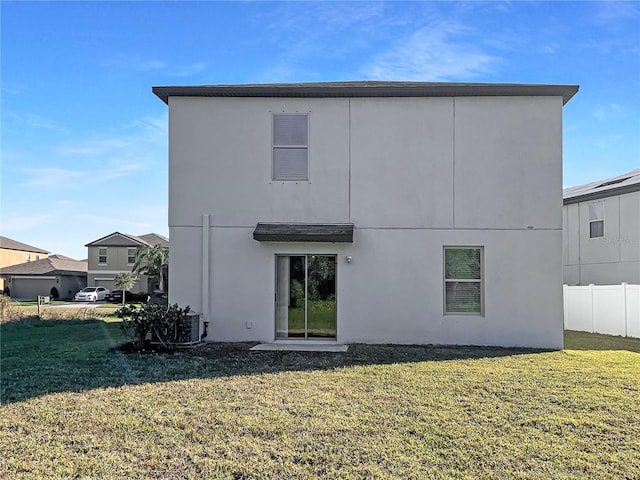 back of house featuring a yard, fence, and stucco siding