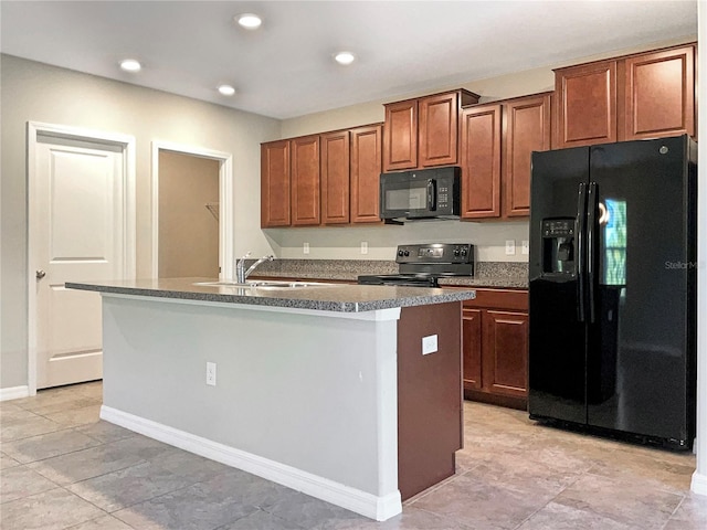 kitchen with an island with sink, dark countertops, brown cabinets, black appliances, and a sink