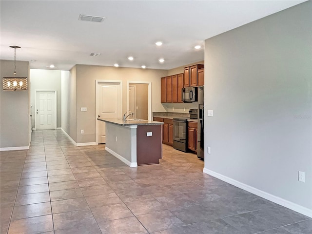 kitchen with baseboards, hanging light fixtures, black appliances, brown cabinetry, and a center island with sink