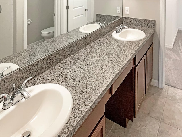 bathroom with double vanity, a sink, and toilet