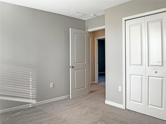 unfurnished bedroom with a closet, visible vents, light carpet, and baseboards