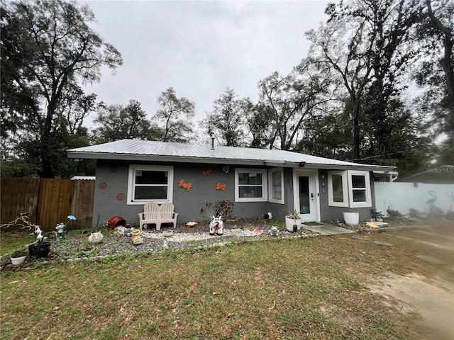 view of front facade with a front yard, metal roof, and fence