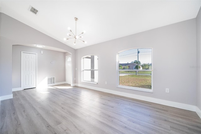 spare room featuring light wood-type flooring, visible vents, and a chandelier