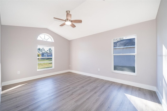 spare room featuring light wood finished floors, ceiling fan, baseboards, and vaulted ceiling