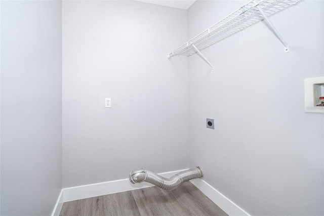 clothes washing area featuring laundry area, baseboards, electric dryer hookup, and wood finished floors