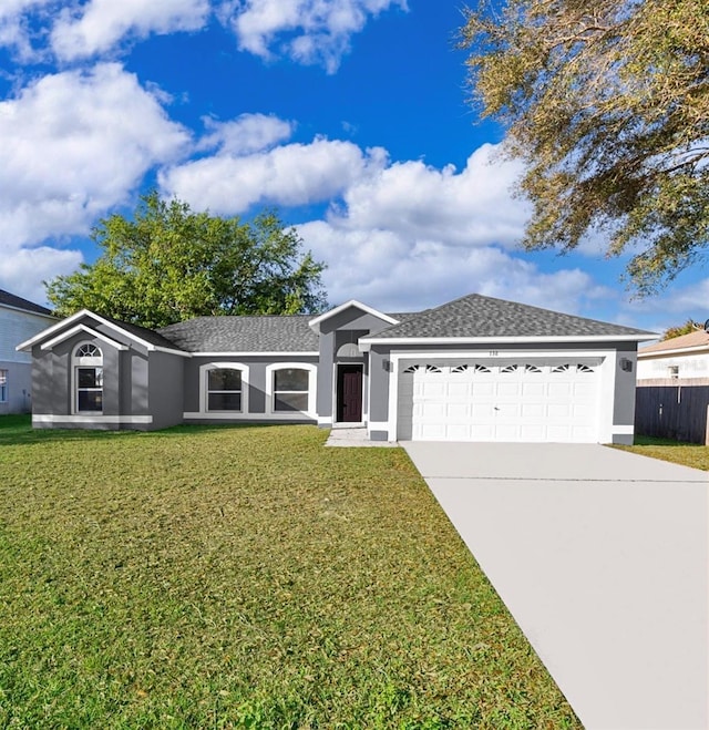 single story home featuring a front lawn, an attached garage, driveway, and stucco siding