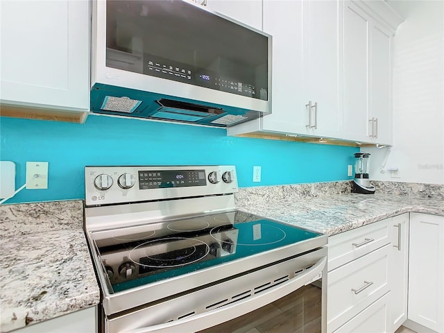 kitchen featuring stainless steel appliances, light stone counters, wood finished floors, and white cabinets