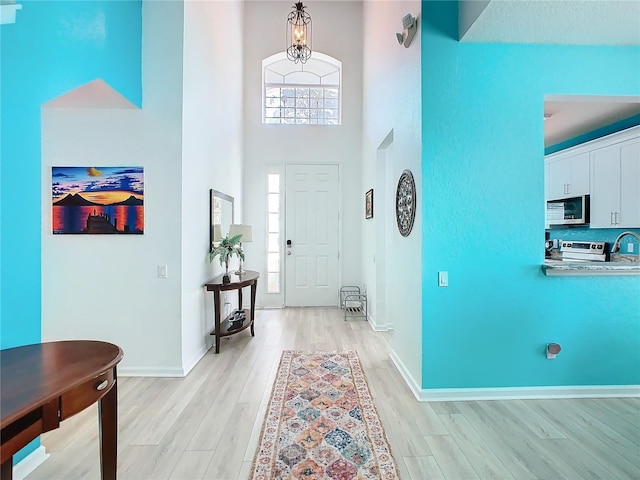 entrance foyer with a high ceiling, light wood-style flooring, and baseboards