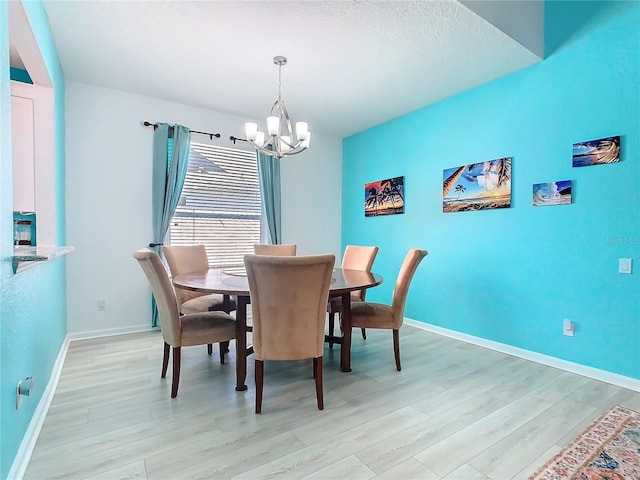 dining area with light wood-style floors, baseboards, and a chandelier