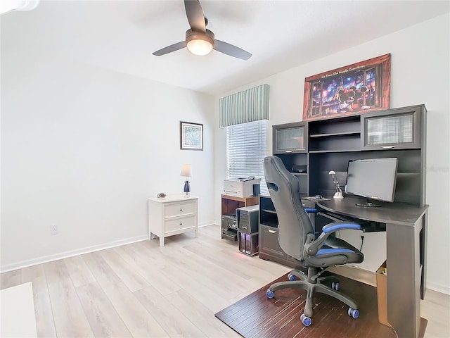 office area with light wood-type flooring, a ceiling fan, and baseboards