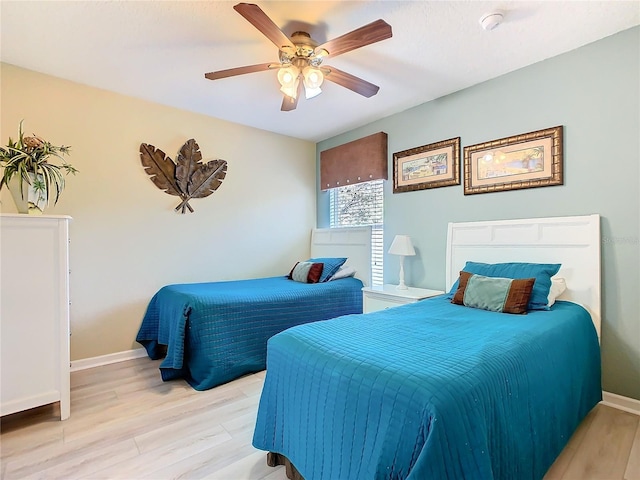 bedroom with ceiling fan, light wood finished floors, and baseboards