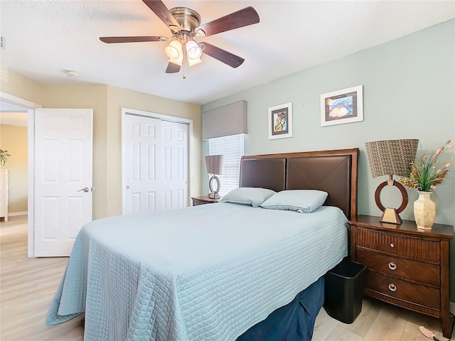 bedroom with light wood-style flooring, ceiling fan, and a closet