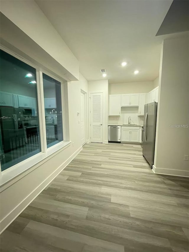 interior space featuring white cabinets, light hardwood / wood-style flooring, stainless steel appliances, and sink