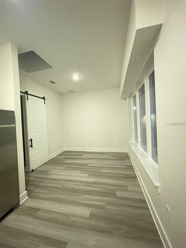 empty room with a barn door and wood-type flooring