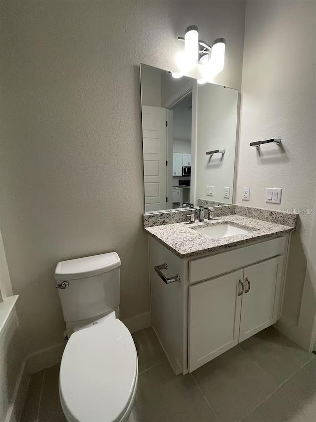 bathroom with toilet, tile patterned floors, and vanity