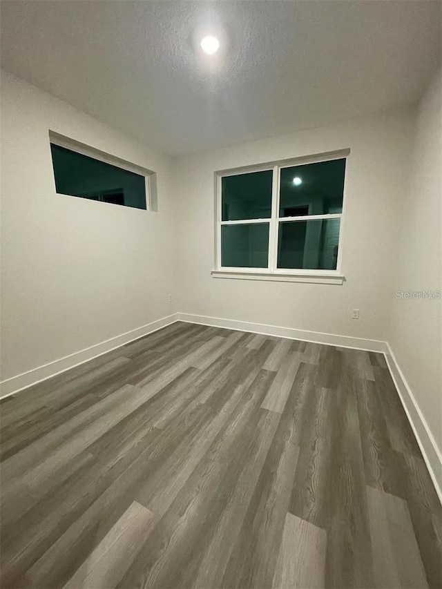 spare room featuring hardwood / wood-style flooring and a textured ceiling