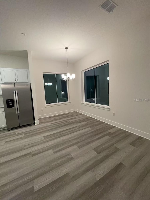 unfurnished dining area with hardwood / wood-style floors and a chandelier