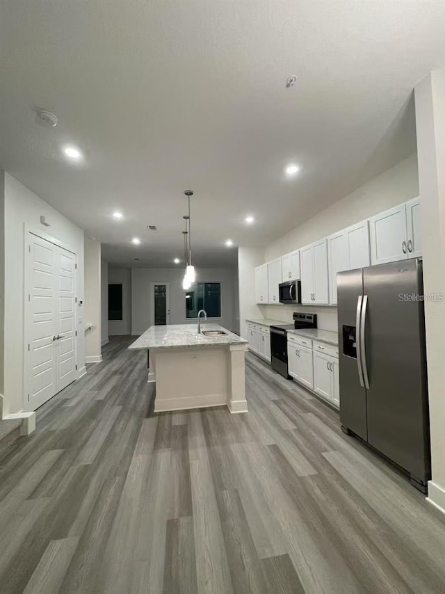 kitchen with a center island with sink, sink, white cabinetry, decorative light fixtures, and stainless steel appliances