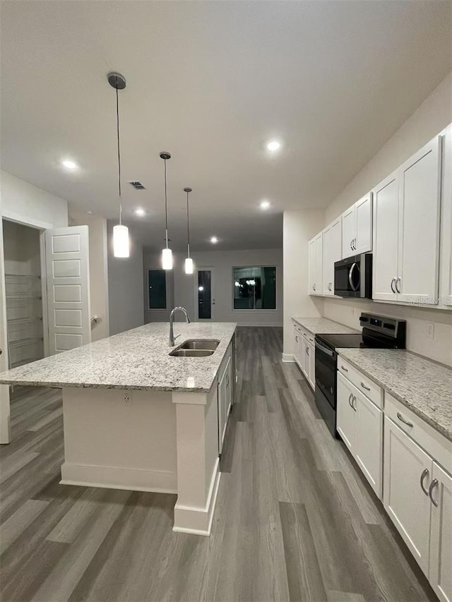 kitchen with white cabinetry, black range with electric stovetop, a kitchen island with sink, sink, and light stone counters