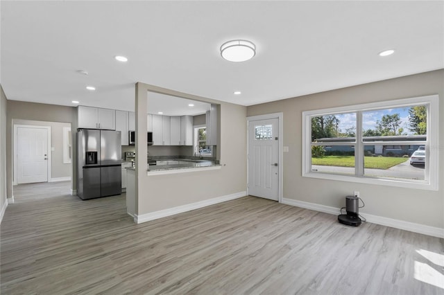 kitchen with baseboards, white cabinetry, stainless steel appliances, and light wood-style flooring