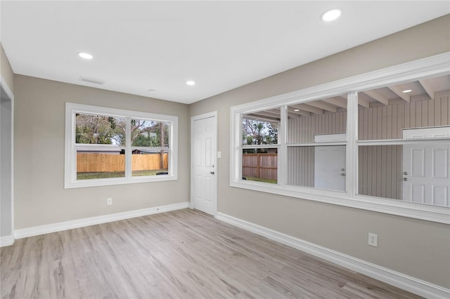 empty room featuring baseboards, light wood-style flooring, visible vents, and a healthy amount of sunlight