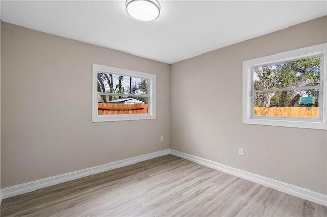 spare room with light wood-style floors, plenty of natural light, and baseboards