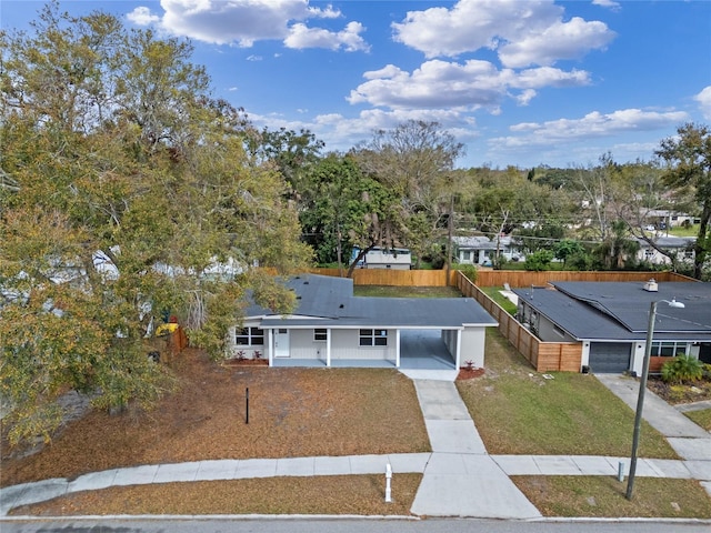 view of front of property featuring concrete driveway, a carport, a front yard, and fence