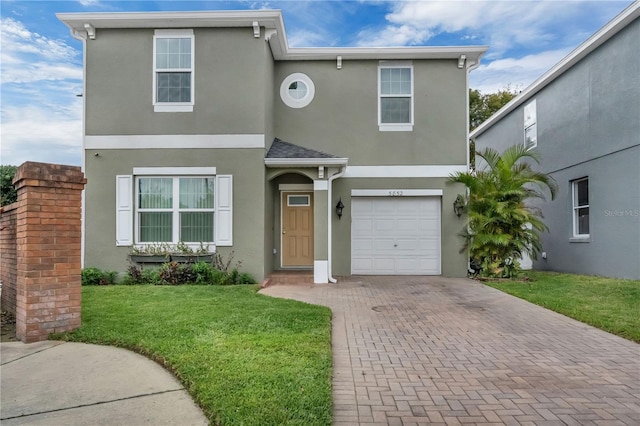 view of front of house with a garage, decorative driveway, a front yard, and stucco siding