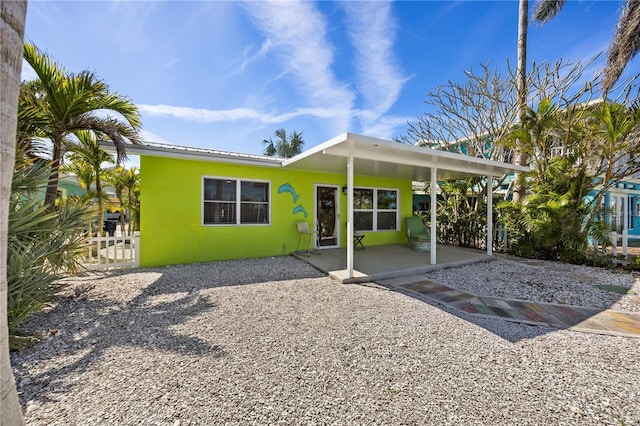 back of house featuring metal roof, a patio, fence, and stucco siding