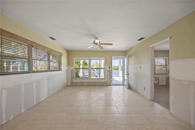 unfurnished room with visible vents, plenty of natural light, and ceiling fan