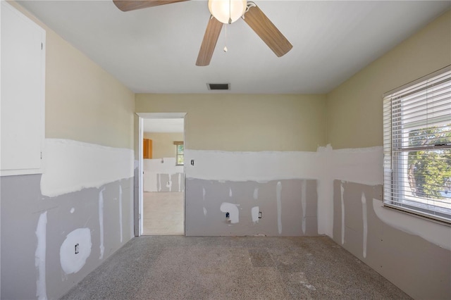 unfurnished room featuring visible vents, carpet floors, ceiling fan, and a wealth of natural light