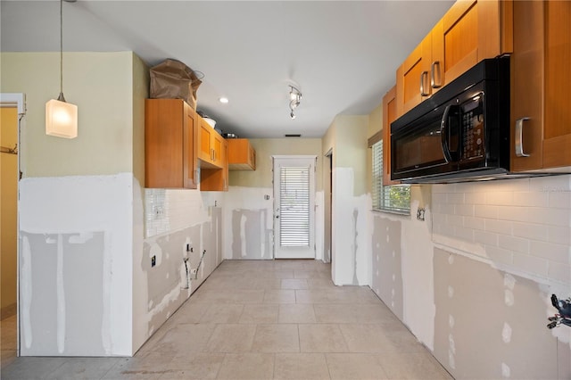 kitchen featuring tasteful backsplash, black microwave, decorative light fixtures, and light tile patterned flooring