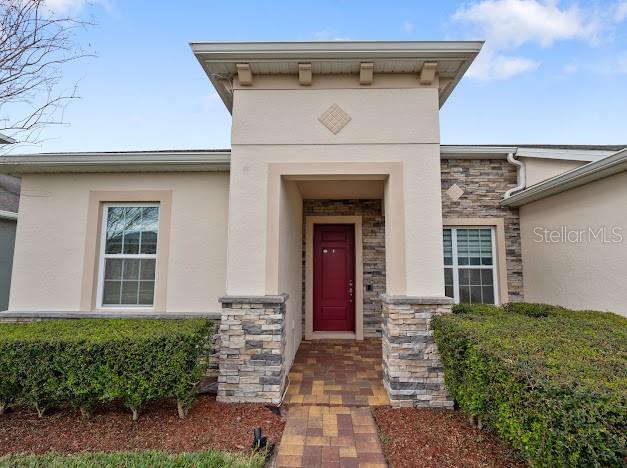 property entrance with stone siding and stucco siding