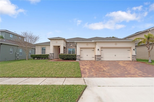 prairie-style house featuring a front lawn, decorative driveway, an attached garage, and stucco siding