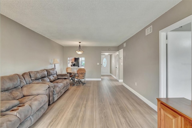 living room with light wood-type flooring and a textured ceiling