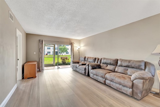 living room with light wood-type flooring and a textured ceiling